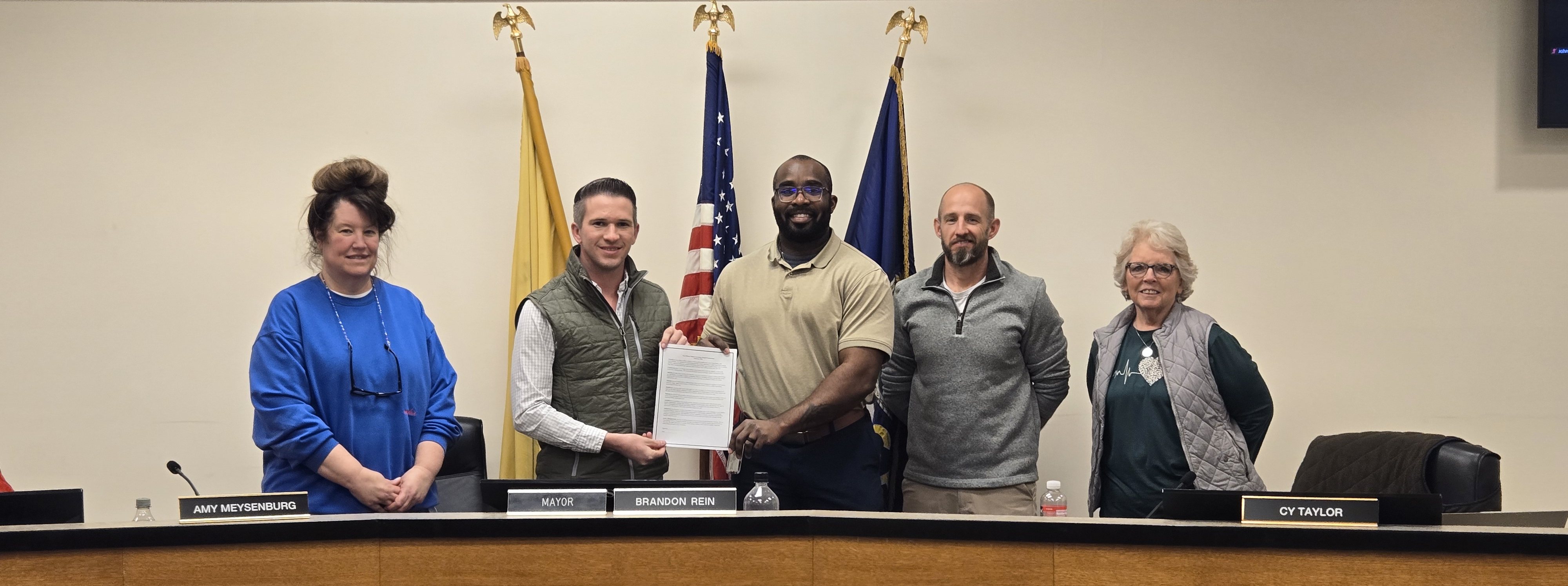 Mayor and community members holding Teen Dating Violence Awareness Month proclamation at City Commission meeting.